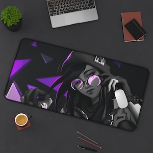 May include: A black and purple gaming mouse pad with a stylized illustration of a woman wearing a black hooded jacket, sunglasses, and a white earbud. The woman is holding a microphone in her left hand and a white mouse in her right hand.