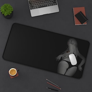Puede incluir: Una alfombrilla de ratón negra con una imagen estilizada de una mujer en traje de baño. La mujer está de espaldas y tiene el pelo largo. La alfombrilla de ratón está sobre una superficie gris.