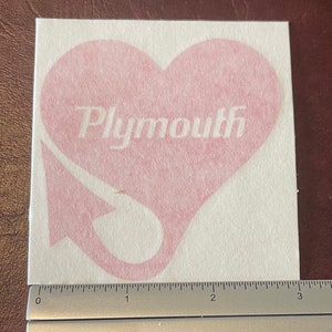 Puede incluir: Pegatina rosa en forma de corazón con una flecha blanca y la palabra "Plymouth" en letras blancas.