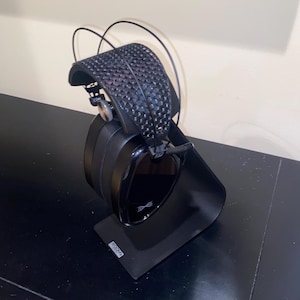 Puede incluir: Auriculares negros con un soporte negro. Los auriculares tienen una diadema negra con un patr&oacute;n texturizado y una copa negra con un acabado brillante. El soporte tiene la palabra "Focal" impresa.