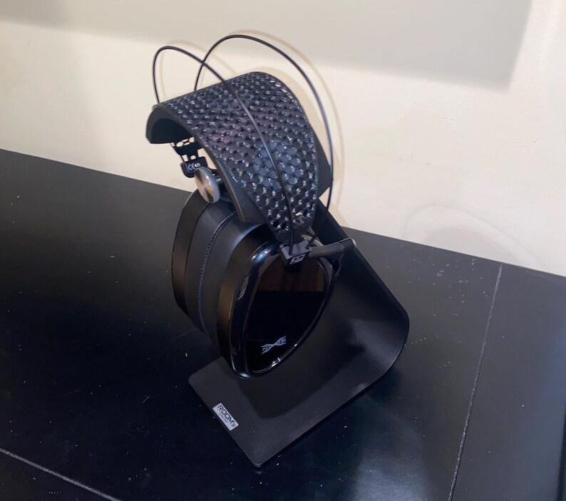 Puede incluir: Auriculares negros con un soporte negro. Los auriculares tienen una diadema negra con un patr&oacute;n texturizado y una copa negra con un acabado brillante. El soporte tiene la palabra "Focal" impresa.