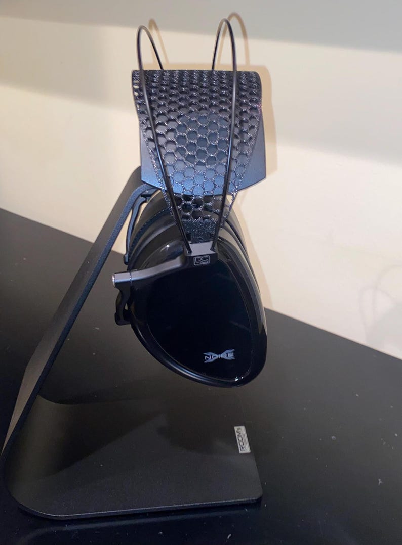Puede incluir: Auriculares negros con un soporte negro. Los auriculares tienen un dise&ntilde;o de malla negra en la diadema y la palabra "Noble" es visible en la almohadilla.