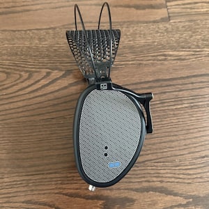 Puede incluir: Auriculares negros con diadema de malla y rejilla de altavoz plateada. Los auriculares tienen un logotipo azul en la rejilla del altavoz.