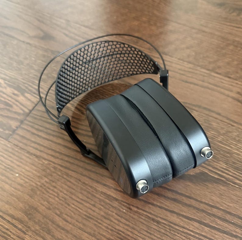 Puede incluir: Auriculares negros con una diadema negra y un dise&ntilde;o de malla negra. Los auriculares tienen un cable negro y dos conectores negros.