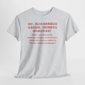Peut inclure: Un t-shirt gris clair avec du texte rouge en anglais et en chinois. Le texte dit : "Bonjour, je fuis le siècle d'humiliation américain. Pourriez-vous m'indiquer où trouver le hamburger le plus proche ?"