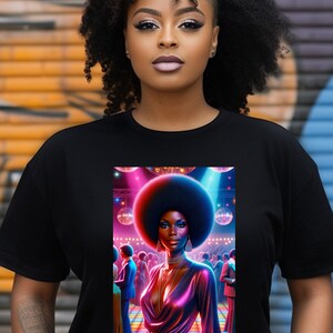 May include: Black t-shirt with a graphic print of a woman with an afro hairstyle dancing in a disco setting. The woman is wearing a pink and purple sequined dress and is surrounded by disco balls and lights.