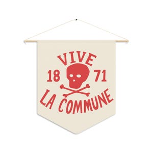 Może przedstawiać: Kremowy baner z czerwonym motywem czaszki i skrzyżowanych piszczeli. Na banerze widnieje napis "VIVE 1871 LA COMMUNE" w kolorze czerwonym. Baner zawieszony jest na drewnianym drążku ze sznurkiem.