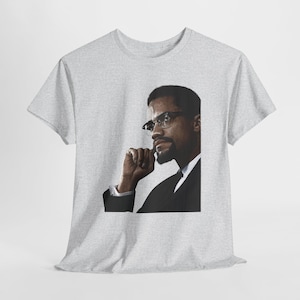 May include: A light grey t-shirt with a portrait of a man in glasses and a suit. The image is a close-up of the man's face and upper body, with a contemplative expression. The t-shirt is made of a soft material.