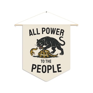 Cream-colored wall banner with the words "ALL POWER TO THE PEOPLE" in bold black letters. A black panther is depicted attacking a yellow and brown snake. The banner is suspended from a wooden rod.
