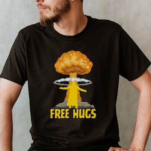 Puede incluir: Una camiseta negra con una imagen de dibujos animados de una nube en forma de hongo con el texto "FREE HUGS" debajo.