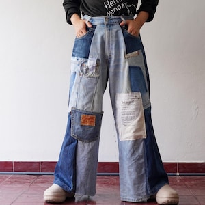 May include: A pair of blue denim jeans with multiple patches sewn on. The jeans are wide-legged and have a high waist.