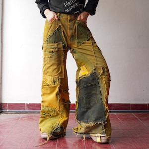 Könnte beinhalten: Gelb-grüne Patchwork-Jeanshose mit mehreren Taschen und Used-Details. Die weit geschnittene Jeanshose hat verschiedene Denim-Patches und ausgefranste Kanten, die eine einzigartige Vintage-Ästhetik erzeugen. Die Hose hat eine hohe Taille und eine lockere Passform.