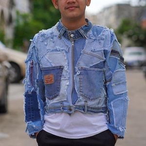 Puede incluir: Chaqueta vaquera patchwork en varios tonos de azul. La chaqueta tiene cierre de cremallera, múltiples bolsillos y un parche de la marca Levi's. El diseño incorpora diferentes piezas de mezclilla, creando un aspecto único y texturizado. La chaqueta se lleva sobre una camiseta blanca.