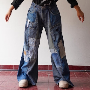 Könnte beinhalten: Weitbeinige Jeans aus Patchwork-Denim. Die Jeans sind dunkelblau und haben verschiedene Denim-Patches, die darauf genäht sind.