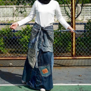 Könnte beinhalten: Ein langer Jeansrock aus mehreren Teilen aus Jeansstoff. Der Rock ist mit einem Jeansgürtel in der Taille gebunden und hat mehrere Taschen.