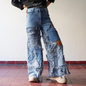 May include: Blue denim jeans with multiple layers of fabric and distressed details. The jeans have a high waist and a wide leg.