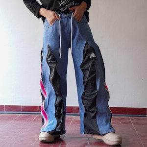 May include: Blue denim pants with black and white panels and pink and white stripes. The pants have an Adidas logo on the right leg.