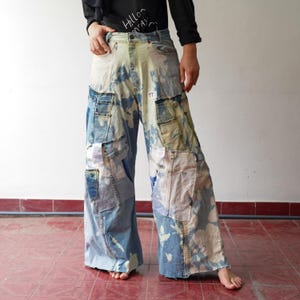 Puede incluir: Vaqueros anchos de patchwork en tonos azules y blancos. Los vaqueros presentan múltiples parches de mezclilla y un efecto desteñido y teñido anudado. Los vaqueros tienen una cintura alta y un corte holgado.
