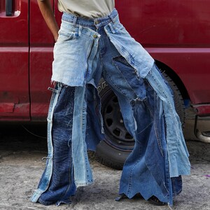 May include: A pair of blue denim jeans with multiple layers of fabric sewn together, creating a unique and layered look. The jeans are distressed and have frayed edges.