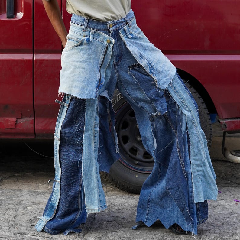 May include: A pair of blue denim jeans with multiple layers of fabric sewn together, creating a unique and layered look. The jeans are distressed and have frayed edges.