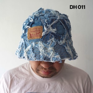 May include: A distressed denim bucket hat with a Levi Strauss & Co. patch. The hat is blue with white frayed edges and the text "DH 011".