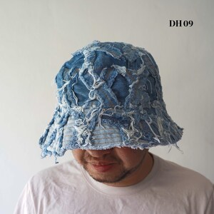 May include: A distressed denim bucket hat in shades of blue. The hat features a patchwork design with frayed edges and white thread accents. The text "DH 09" is visible on the upper right side of the image.