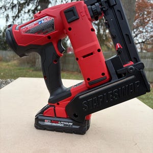 Może przedstawiać: Czerwono-czarny bezprzewodowy zszywacz z napisem "STAPLES/MAP" z boku. Narzędzie ma czarny uchwyt i czerwony akumulator z napisem "M18 REDLITHIUM HIGH OUTPUT CP3.0".