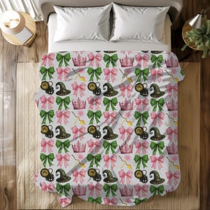 Peut inclure: Un ensemble de literie blanc avec un motif répété de nœuds roses, de nœuds verts, de chapeaux de sorcière et de couronnes. Le motif est présent sur les taies d'oreiller et la housse de couette.