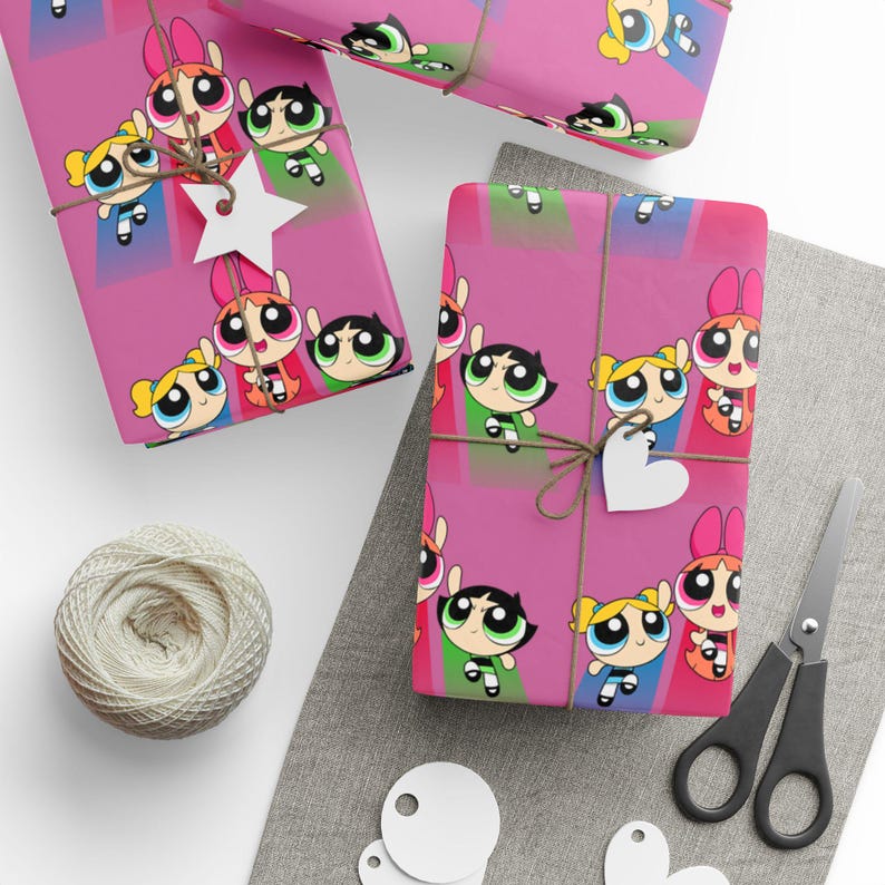 May include: Pink wrapping paper featuring the Powerpuff Girls cartoon characters. The gifts are tied with twine and adorned with white star and heart-shaped tags. A ball of twine and scissors are also visible.