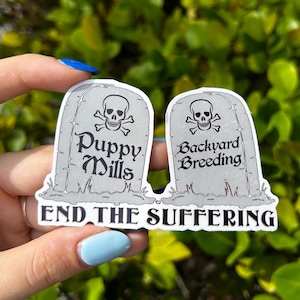 May include: Two white tombstone stickers with black text and skull and crossbones graphics. The text on the tombstones reads "Puppy Mills" and "Backyard Breeding". Below the tombstones is the text "End the Suffering".