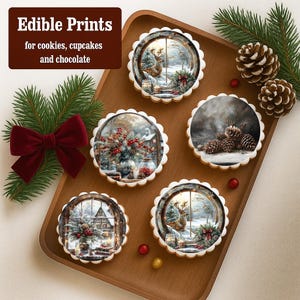 May include: A wooden tray holds six round cookies with winter-themed edible prints. The prints depict snowy scenes with deer, pine cones, and floral arrangements. The text "Edible Prints for cookies, cupcakes and chocolate" is in the upper left corner. A red bow and pine branches are on the left.