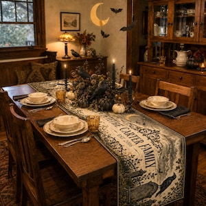 May include: A wooden dining table set with a long runner featuring the text THE CARTER FAMILY EST. 2016, surrounded by white bowls on plates, black taper candles, small pumpkins, and black bird figures, with hanging moon and bat decorations.