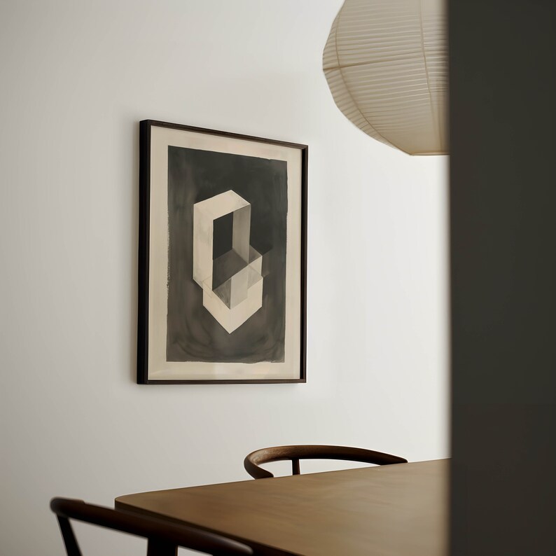 May include: A framed black and white abstract art print of a geometric shape, hanging on a white wall above a wooden table with two chairs.