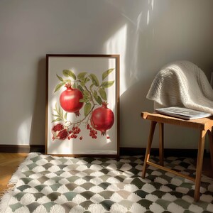 May include: A framed botanical illustration of a pomegranate branch with three red pomegranates. The illustration is set against a white background and framed in a brown wood frame.