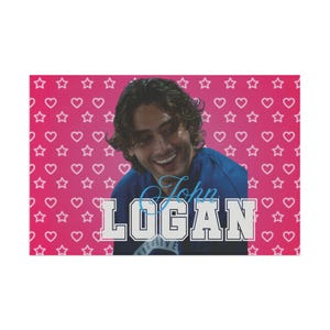 May include: A rectangular poster featuring a pink background with a repeating pattern of white hearts and stars. Centered is a photograph of a person with dark hair smiling, overlaid with the blue script text John and the white block text LOGAN.