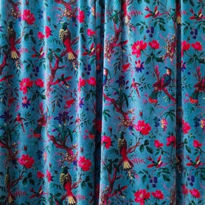 Könnte beinhalten: Türkisfarbener Stoff mit einem lebendigen Blumen- und Vogelmuster. Das Design zeigt rote Blüten, grüne Blätter und bunte Vögel auf Ästen. Der Stoff eignet sich wahrscheinlich für Vorhänge oder Polster.