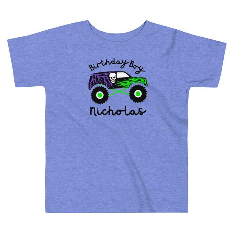 May include: A blue toddler t-shirt with a green monster truck graphic. The truck has a skull and flames. The text "Birthday Boy Nicholas" is printed on the shirt.