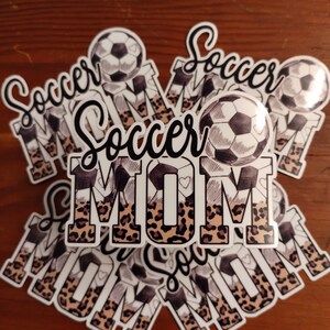 May include: A stack of stickers with a leopard print design and the words "Soccer Mom" and a soccer ball.