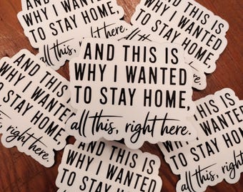 May include: A collection of white stickers with black text. Each sticker has the phrase "AND THIS IS WHY I WANTED TO STAY HOME, all this, right here." The stickers are arranged on a wooden surface.