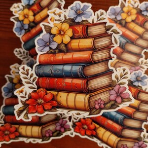 May include: A stack of vintage books with worn leather covers, adorned with colorful flowers in shades of red, yellow, blue, and purple. The books are arranged in a pile, with the top book being the oldest and the bottom book being the newest.