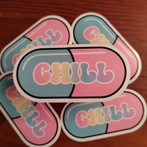 May include: Five pastel blue and pink pill-shaped stickers with the word "CHILL" in rainbow colors. The stickers are arranged in a semi-circle.