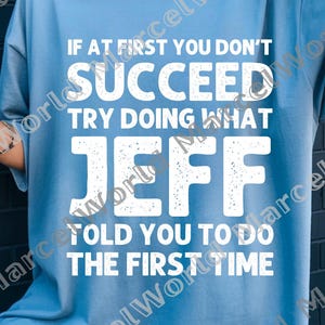 May include: A light blue t-shirt with the text "IF AT FIRST YOU DON'T SUCCEED TRY DOING WHAT JEFF TOLD YOU TO DO THE FIRST TIME" in white block letters. The shirt is a casual style.