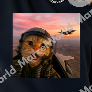 Peut inclure: Sweat-shirt noir avec un motif d'un chat portant un casque de pilote, avec un avion à réaction en arrière-plan sur fond de coucher de soleil. Le texte "PNG & SVG" est inclus.