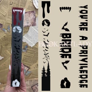 Może przedstawiać: Czarno-biała okładka książki z czarno-białą ilustracją wilka, nietoperzy i drzew. Na okładce nadrukowany jest tekst "You're a privilege".