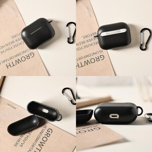 May include: Black protective cases for wireless earbuds, with silver carabiner clips. The cases are shown open and closed, with a sleek, minimalist design. The word "GROWTH" is visible on the background.