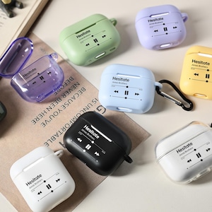 May include: A collection of colorful AirPod cases in various colors, including green, purple, blue, and yellow. Each case features the word "Hesitate" and a music player graphic. The cases are designed to protect and personalize wireless earbuds.