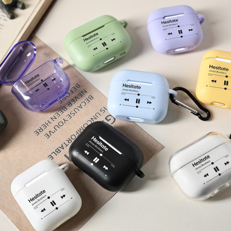 May include: A collection of colorful AirPod cases in various colors, including green, purple, blue, and yellow. Each case features the word "Hesitate" and a music player graphic. The cases are designed to protect and personalize wireless earbuds.