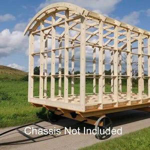 Puede incluir: Un marco de madera para una pequeña casa o cabaña. El marco está hecho de madera clara y tiene un techo curvo. El marco está sentado en un remolque de plataforma. El texto "Chassis Not Included" es visible en la imagen.