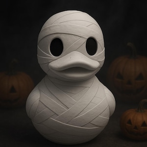 May include: A white mummy duck figurine with black eyes and a beak, wrapped in bandages. The duck is surrounded by three carved orange pumpkins, creating a Halloween theme.
