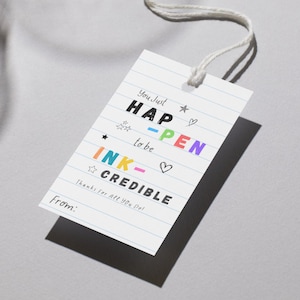 May include: A white gift tag with a string, featuring the words "You Just HAPPEN to be INK-CREDIBLE" in various colors and fonts. The tag has a lined paper design and includes the text "Thanks For All You Do" and "From:"